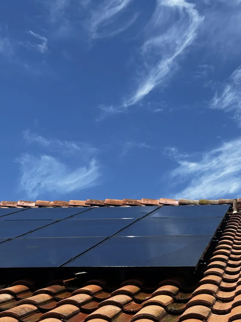 Solar panels on a tile roof being cleaned under a clear blue San Diego sky by SeaBreeze Home Service